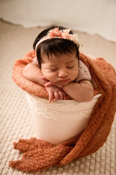 Newborn baby girl asleep in a bucket with a rust wrap